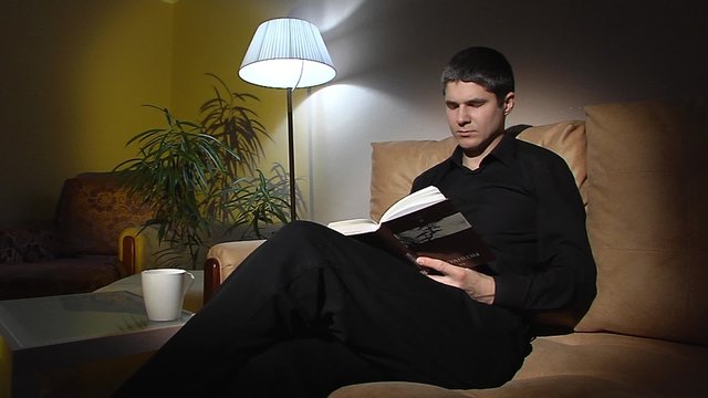 Man in black reading a book. 2 shots