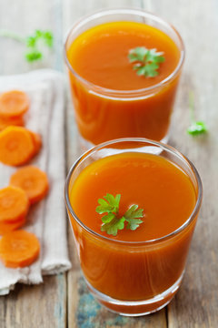 Fresh carrot juice in glass on wooden table, healthy vegetable drink
