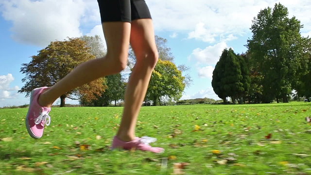 Young female runners legs in slow motion moving along a running field