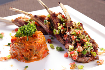 Grilled lamb ribs with herbal sauce on white ceramic tray