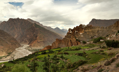 Small village on mountain valley slope with river and farm in In