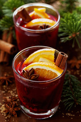 Christmas mulled wine or gluhwein with spices and orange slices on rustic table, traditional drink on winter holiday, magic light, selective focus