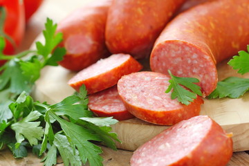 Smoked sausage with spices and vegetables on wooden table