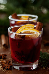 Christmas mulled wine or gluhwein with spices and orange slices on rustic table, traditional drink on winter holiday, magic light, selective focus