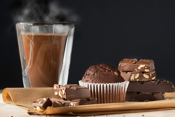 Hot delicious chocolate, stack of dark chocolate, muffin.