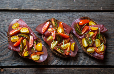 Bruschetta with dried meat and colorful cherry tomatoes, Italian appetizers