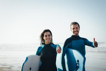 Successful couple of surfers. Surfing and outdoor sport lifestyle concept. Woman and man after...