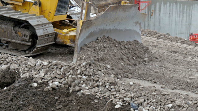 A bulldozer pushing some stones on the road. It is a under construction road in the street of Estonia