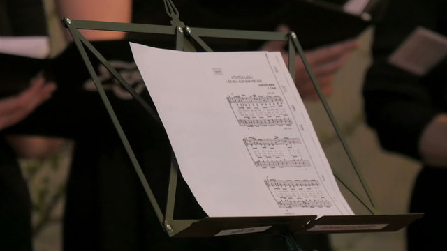 A conductors copy of the music sheet. Children are singing on the back while the conductor is on the front