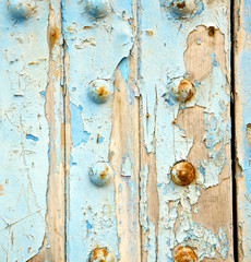 dirty stripped paint in the blue wood door and rusty nail