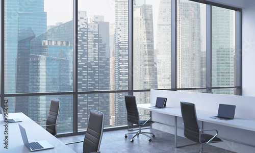 Workplaces in a bright modern open space office white tables equipped with modern laptops and Workplaces in a bright modern open space office white tables equipped with modern laptops and