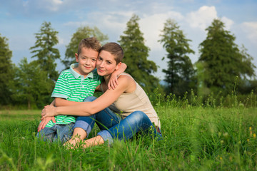 Naklejka na ściany i meble Mother and son posing for an outdoor portrait, smiling