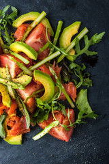 Avocado and trout salad on the black stone vertical top view
