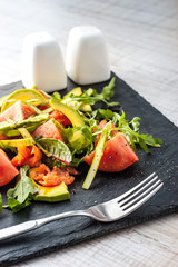 Vegetable salad with trout on the black stone with fork