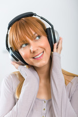 Fototapeta premium Portrait of a beautiful girl with headphones isolated ong grey background