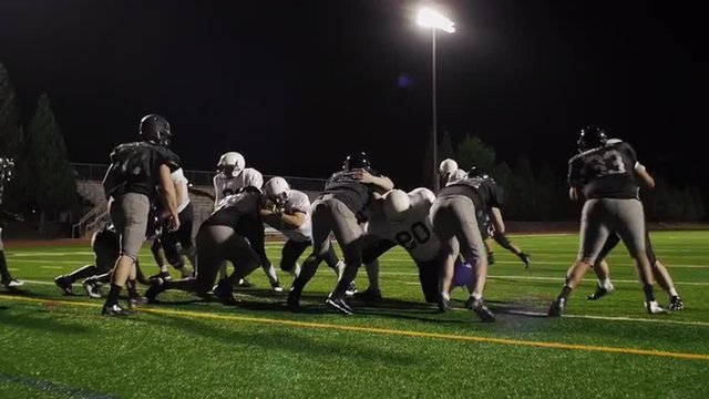 A football player tries to jump over someone and gets pushed over over another player
