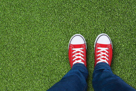 Green grass field with feet wearing red sneakers