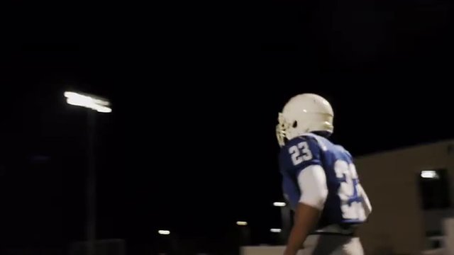 Two football players running a drill on the field at night
