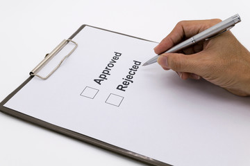 Man hand with pen over document, select Approved or Rejected.