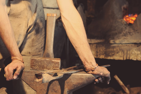 Blacksmith working metal with hammer