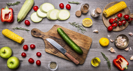 cutting board, lay around the cucumbers, peppers, tomatoes on a branch, lemon, corn, zucchini, apples, butter, spices and herbs, Healthy foods, cooking and vegetarian concept.