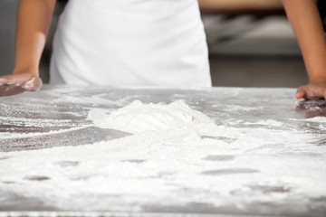 Dough On Table With Baker Standing In Bakery
