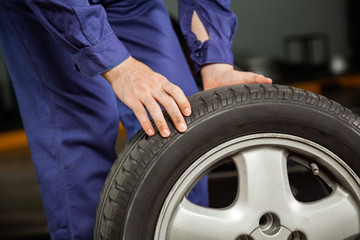 Fototapeta premium Mechanic Holding Tire At Garage