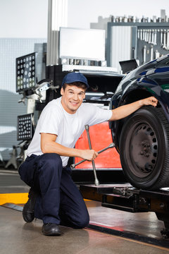 Smiling Mechanic Holding Rim Wrench By Car