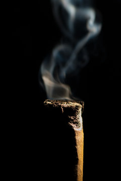 Close-up of a smoking cigar butt against a black background