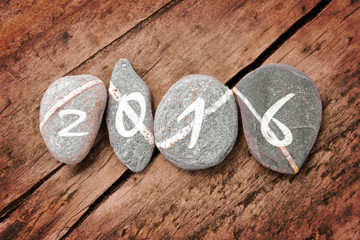 2016 written on a line of stones on a wooden background