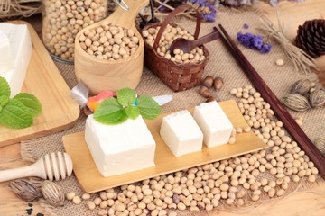 Tofu and soybeans on wood background.