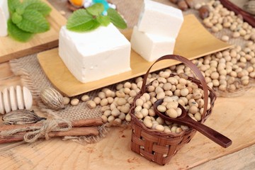 Tofu and soybeans on wood background.