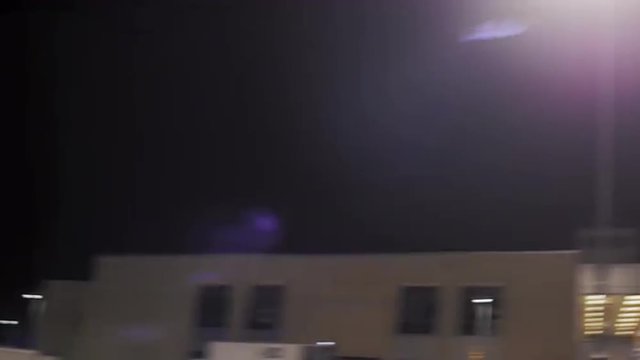 The camera spins around a football player running a drill on the field at night
