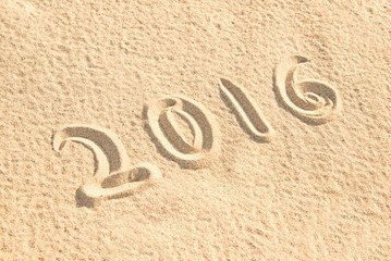 Close up on 2016 written in the sand of a beach