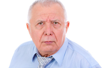 Close-up portrait of serious and strict senior old businessman, dressed in blue shirt and tie, isolated on white background. Human emotions and facial expressions