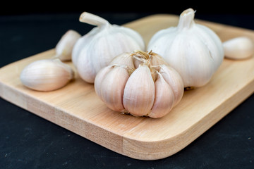 garlic clove, garlic bulb place on chopping block on black backg