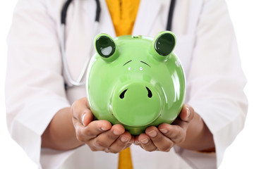 Female doctor holding piggy bank