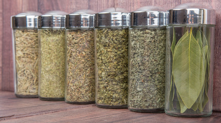 Dried laurel leaves, thyme, basil, oregano, rosemary, parsley over wooden background