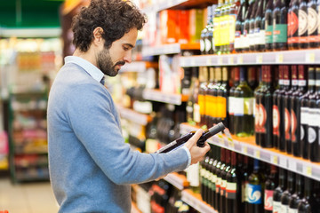 Man in a supermarket choosing a wine bottle