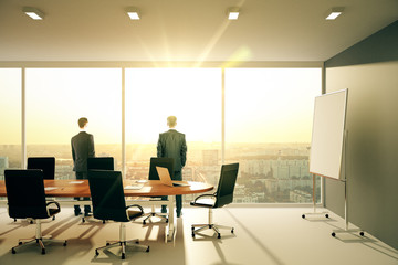 Businessmen in sunny conference room with furniture and cityview