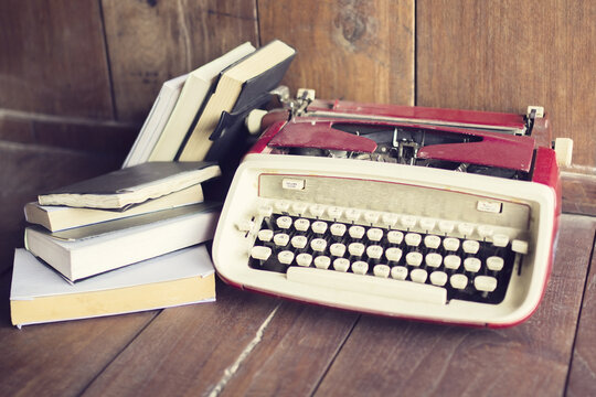 Old style typewriter with books on wooden floor