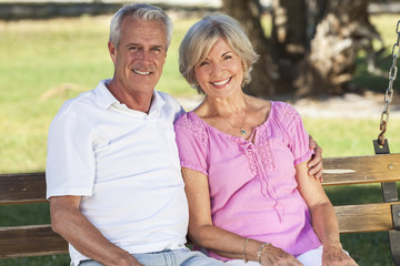 Happy Senior Couple Sitting on Bench in Sunshine