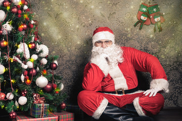 Santa Claus sitting near Christmas tree at eve night