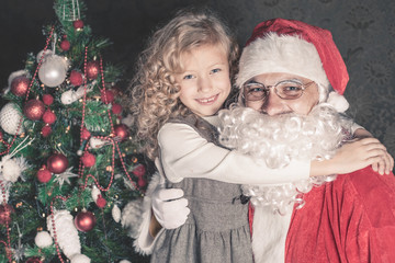 Little girl hugs Santa Claus at Christmas night