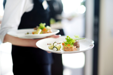Obraz na płótnie Canvas Waiter carrying plates with meat dish