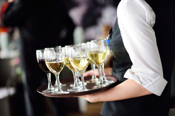 Waitress with dish of champagne and wine glasses