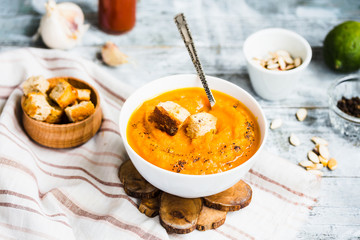 Pumpkin soup with carrots, croutons in a white dish, vegetarian