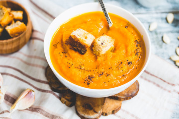 Pumpkin soup with carrots, croutons in a white dish, vegetarian