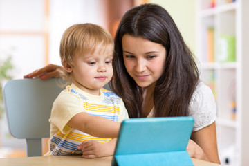 Mother and son child playing with tablet computer indoors