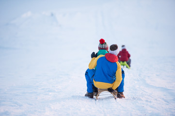 Junge Familien beim Schlittenfahren im Winter